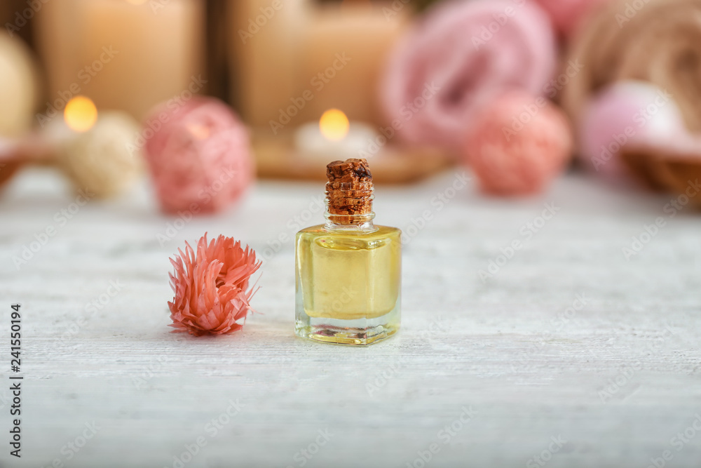 Bottle of essential oil and flower on table