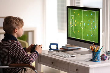 Wall Mural - Cute little boy playing computer game at home