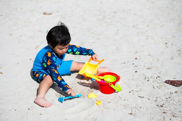 Little boy baby playing with sand on sea shore, Happy time on summer beach