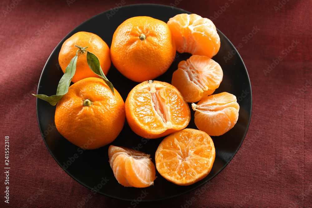 Plate with tasty tangerines on table