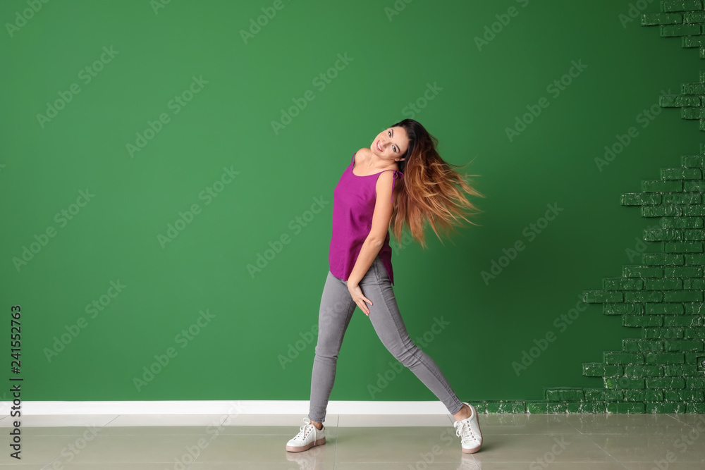 Young woman dancing near color wall