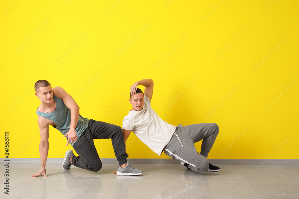 Young men dancing near color wall