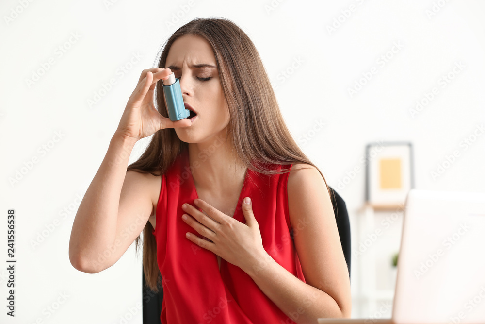 Young woman with inhaler having asthma attack at home