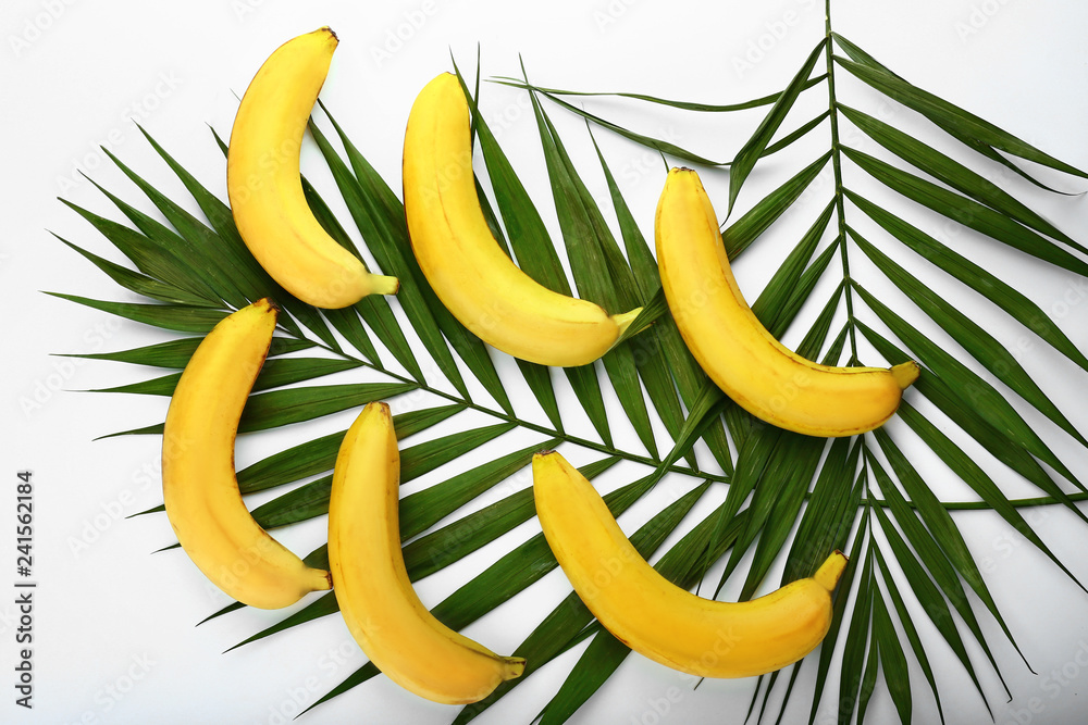 Ripe sweet bananas and palm leaves on white background