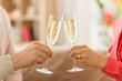 valentines day, celebration and engagement concept - close up of couple hands clinking champagne glasses