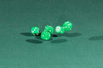 Five green dices falling on a green table