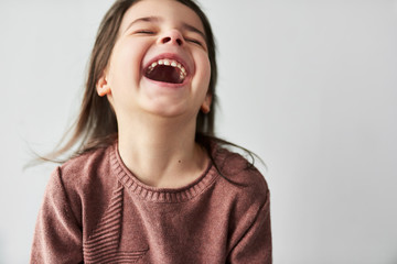 Studio closeup horizontal portrait of happy beautiful little girl smiling joyful and wearing sweater isolated on a white studio background. Mother's Day concept