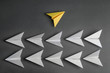 © New Africa - Different color paper plane flying away from others on dark background, top view