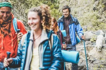 Young people doing trekking excursion in mountain's path - Hikers walking in nature path outdoor - Survival,travel and adventure concept - Focus on right man face