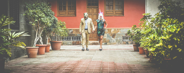 Wall Mural - Crazy senior couple walking around city street wearing t-rex and chicken mask