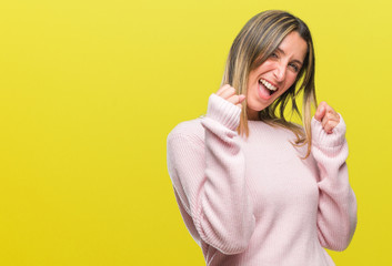 Young beautiful woman wearing winter sweater over isolated background very happy and excited doing winner gesture with arms raised, smiling and screaming for success. Celebration concept.