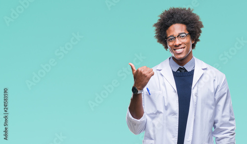 Fotografía Afro american doctor scientist man over isolated background smiling with happy face looking and pointing to the side with thumb up