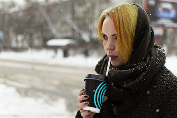 Woman drinking coffee in the street in winter.