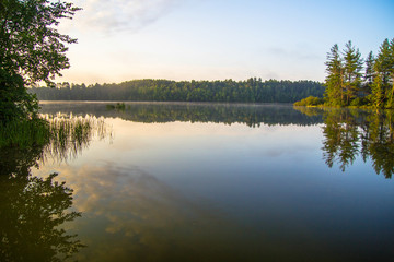 Wilderness Lake Sunrise. Sunlight glows over the horizon of a wilderness lake in northern Michigan. Horizontal orientation with copy space in the foreground.