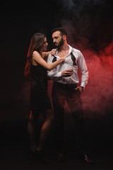 Wall Mural - passionate woman hugging man with glass of whiskey in red smoky room