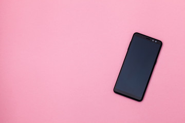 Black smartphone is lying on a pink background. Mock up of modern technology, mobile communications. Empty place for input the text. Top view.  