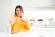 © Krakenimages.com - Young beautiful woman drinking a cup of coffee at home afraid and terrified with fear expression stop gesture with hands, shouting in shock. Panic concept.