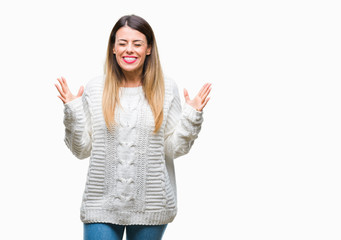 Young beautiful woman casual white sweater over isolated background celebrating mad and crazy for success with arms raised and closed eyes screaming excited. Winner concept