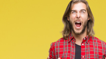 Sticker - Young handsome man with long hair over isolated background crazy and mad shouting and yelling with aggressive expression and arms raised. Frustration concept.