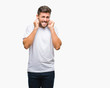 © Krakenimages.com - Young handsome man over isolated background covering ears with fingers with annoyed expression for the noise of loud music. Deaf concept.