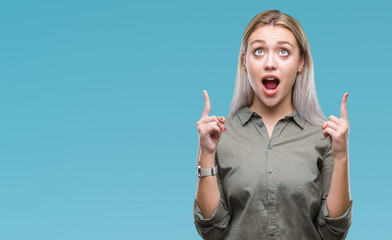 Young blonde business woman over isolated background amazed and surprised looking up and pointing with fingers and raised arms.