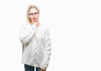 Sticker - Young beautiful blonde woman wearing glasses over isolated background with hand on chin thinking about question, pensive expression. Smiling with thoughtful face. Doubt concept.