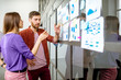 © rh2010 - Young man and woman dressed casually working with some statistics on the glass wall in the office