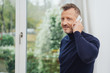 © contrastwerkstatt - Man talking by telephone, standing against window