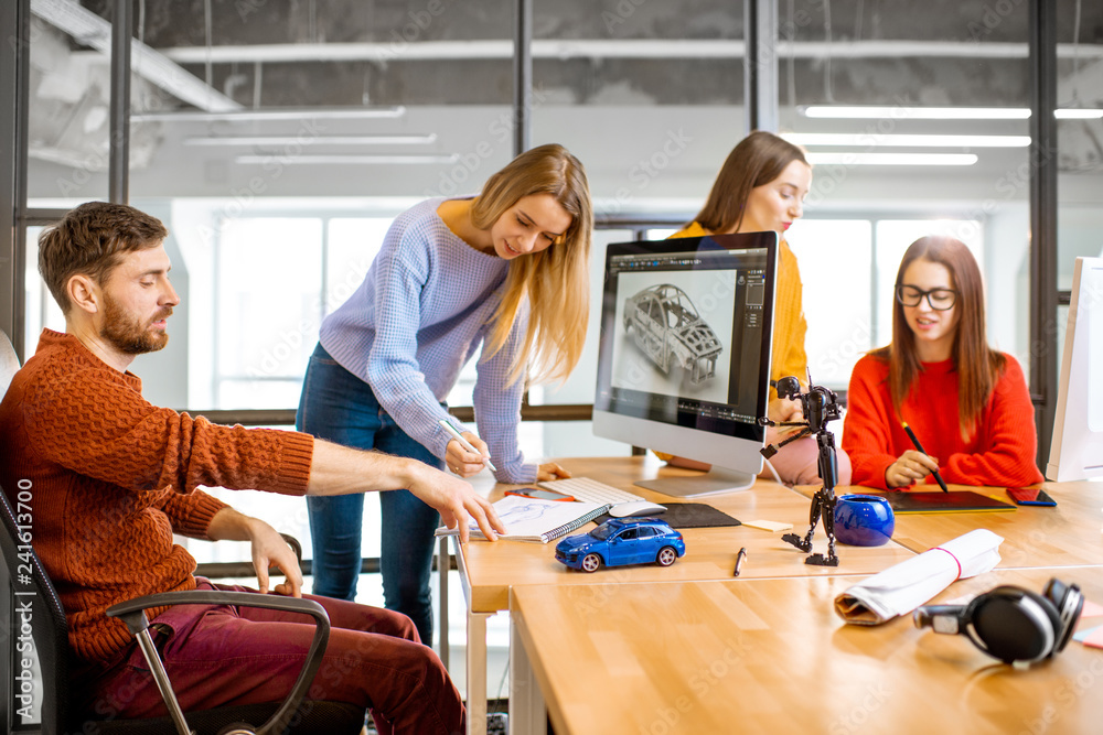 Group of young creative coworkers designing a car model at the working ...