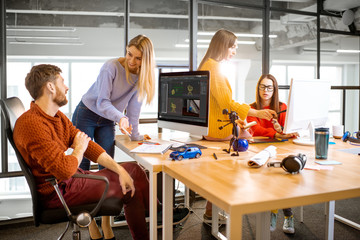 Group of a young coworkers dressed casually modeling 3d project working on computers in the modern office