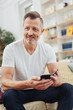 © contrastwerkstatt - Portrait of man with cellphone, sitting on couch