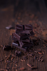 Column of dark or bitter or milk chocolate on a wood background.