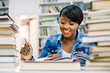 © sofiko14 - Pretty teenage black african college student girl studying and reading a book in college library