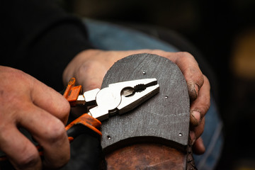 close up of the hands of a man repairing shoes