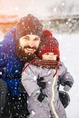 Canvas Print - Dad with child son or daughter outdoor in winter. Handsome young dad and his little cute daughter are having fun outdoor in winter. Enjoying spending time together. Family concept.