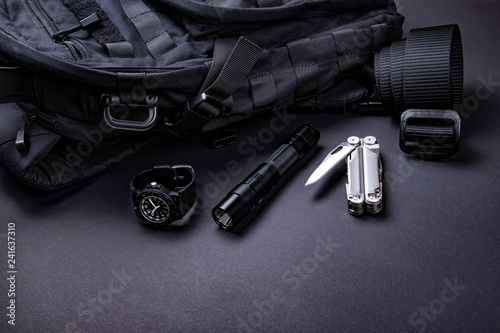 Fotomural Everyday carry (EDC) items for men in black color - backpack, tactical belt, flashlight, watch and silver multi tool