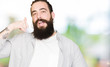 © Krakenimages.com - Young man with long hair, beard and earrings smiling doing phone gesture with hand and fingers like talking on the telephone. Communicating concepts.