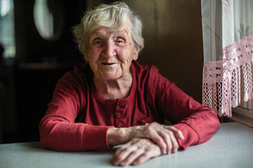 Wall Mural - Emotions of elderly woman sitting at the table. 90 year old.