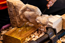 Closeup Of A Carpenter's Hands Working With A Chisel And Hammer On Wooden Buddha Sculpture