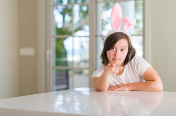 Sticker - Down syndrome woman at home wearing easter rabbit ears pointing with finger to the camera and to you, hand sign, positive and confident gesture from the front