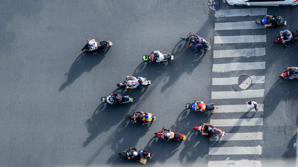 Wall Mural - top aerial view of blur bikers ride the motorcycles to pass pedestrian crosswalk on road with the traffic pattern signage on the street