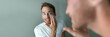 © Maridav - Man skin care putting moisturizer cream on face. Male beauty skincare concept. Young handsome adult looking in the bathroom mirror applying anti-aging lotion. Healthy lifestyle banner panorama.