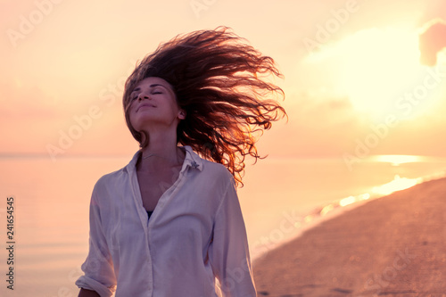 Fotografía Beautiful young woman girl with flying curly hair on the background of a tropica