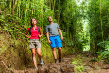 Forest Hike Hikers Hiking In Rainforest Trail In Hawaii. Interracial Couple Walking In Travel Adventure. Asian Woman, Caucasian Man Active Lifestyle. Excursion Activity.