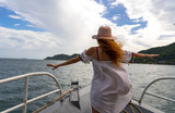Fototapeta Dziecięca - Red hair girl stayiing on a cruise boat in a white dress and hat,travel  in Phu Quoc island near cable cars 