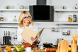 © LIGHTFIELD STUDIOS - pensive beautiful mature woman reading recipe book for cooking in kitchen