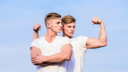 Wall Mural - Attractive twins. Handsome strong twins. Men twins muscular brothers sky background. Men strong muscular athlete bodybuilder posing confidently in white shirts. Sport lifestyle and healthy body