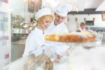 Mature chef coworkers standing at dessert counter in restaurant