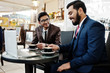 © AS Photo Family - Two indian business man in suits sitting at office on cafe, looking at laptop and drinking coffee.