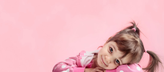 Portrait of a cute little girl with pigtails on pink background.